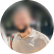Femme aux longs cheveux bruns, vêtue d'une chemise claire boutonnée, souriant doucement à la lumière naturelle.